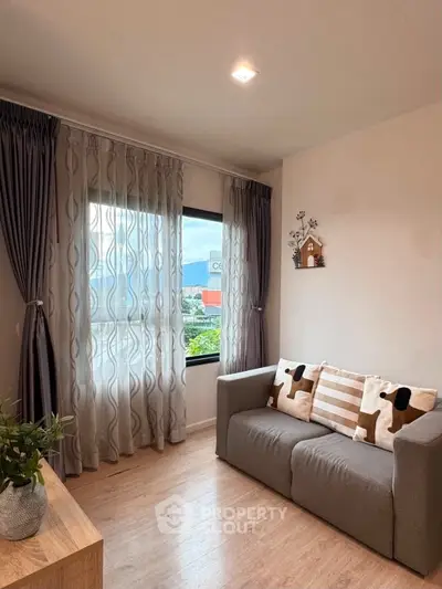 Cozy living room with stylish decor and large window offering natural light and scenic views.