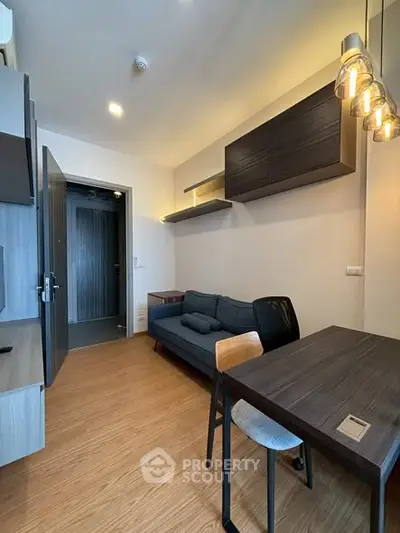 Modern living room with stylish lighting and cozy seating in a compact apartment.