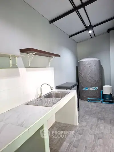 Modern kitchen with sleek sink and storage, featuring a water tank and minimalist design.