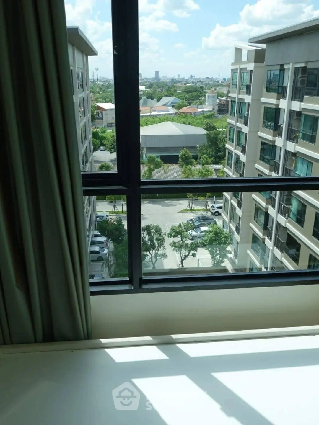 Stunning urban view from high-rise apartment window with lush greenery and cityscape.