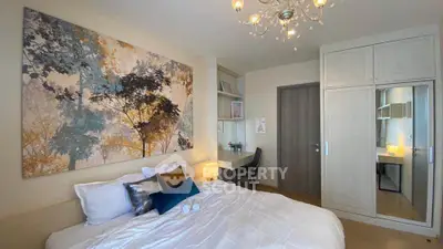 Elegant bedroom with modern decor and large artwork, featuring a cozy bed and stylish chandelier.