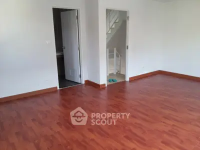 Spacious empty room with wooden flooring and two doorways, ideal for customization.