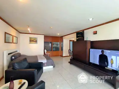 Spacious living room with modern decor and large TV, perfect for relaxation.