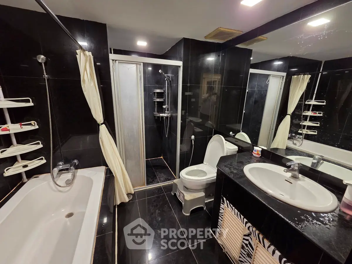 Luxurious black-tiled bathroom with bathtub and modern fixtures