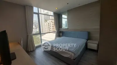 Modern bedroom with large window offering city view in high-rise apartment.