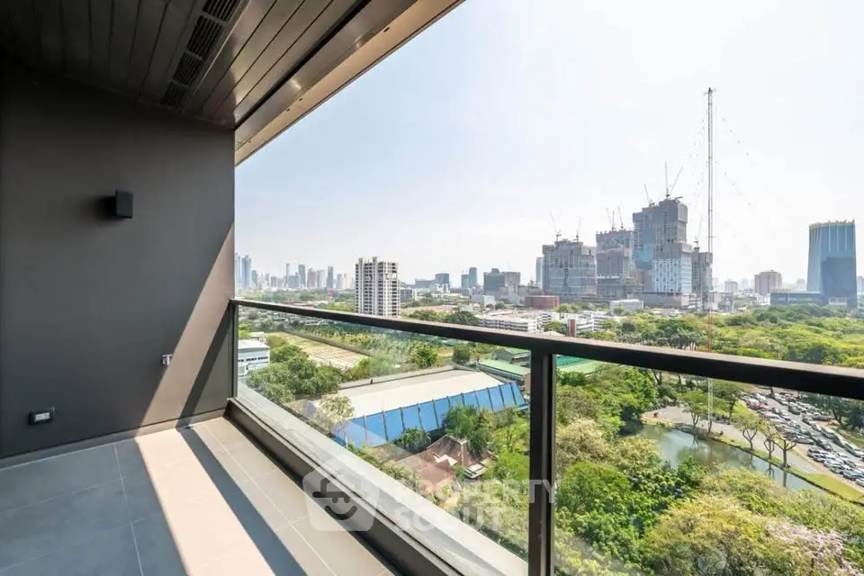 Stunning cityscape view from modern balcony with glass railing and lush greenery.