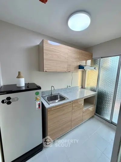 Modern kitchen with sleek cabinetry and compact fridge in a bright, minimalist design.