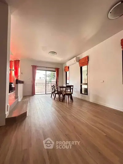 Spacious living room with wooden flooring and natural light, ideal for family gatherings.