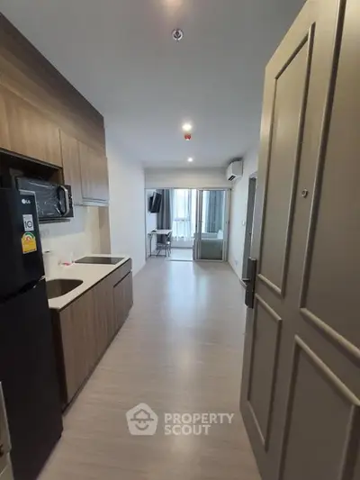 Modern apartment entrance leading to a sleek kitchen and cozy living area with natural light.