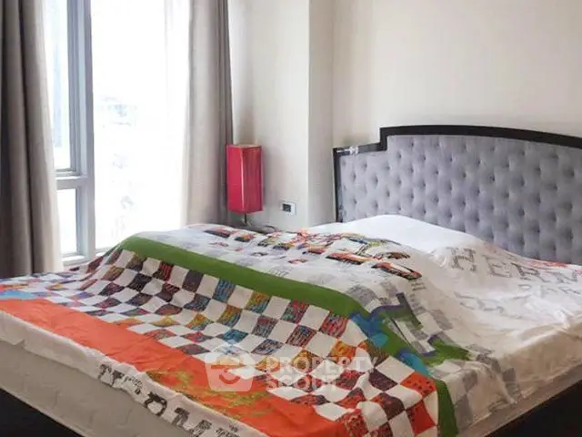 Cozy bedroom with stylish headboard and colorful quilt in bright apartment.