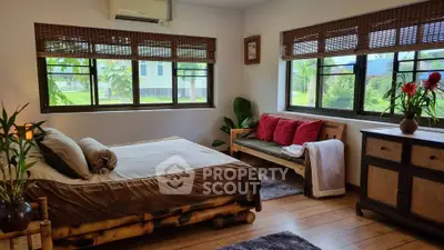 Charming bedroom with natural light and cozy decor, featuring bamboo bed and garden views.