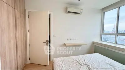 Bright bedroom with city view, air conditioning, and wooden flooring.