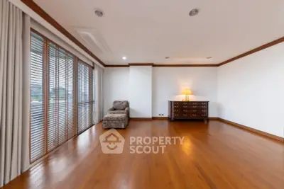 Spacious living room with wooden flooring and large windows for natural light.