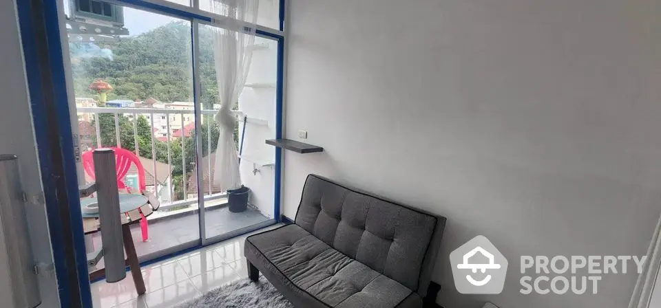 Cozy living room with balcony and scenic view, featuring modern sofa and outdoor seating.