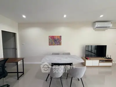 Modern living room with sleek furniture and wall art, featuring a TV and air conditioning.