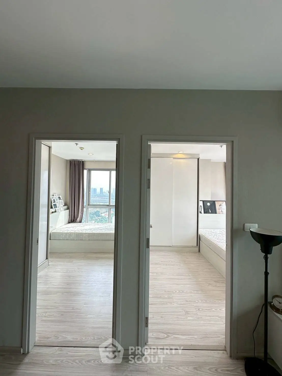 Spacious modern apartment with two bedrooms and city view, featuring sleek wooden flooring and ample natural light.