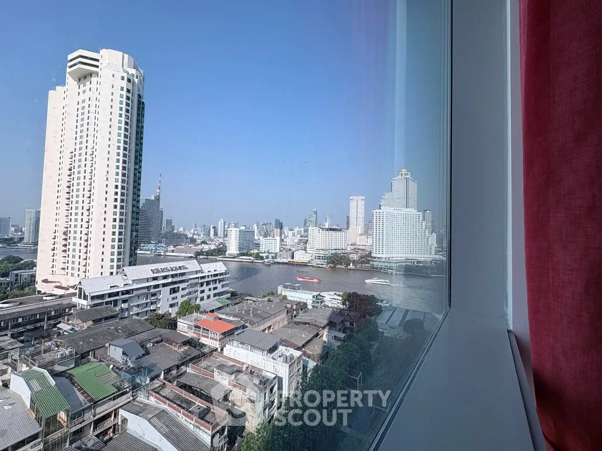 Stunning cityscape view from a high-rise window overlooking a river and urban skyline.