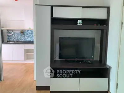 Modern living room with sleek TV unit and view into stylish kitchen