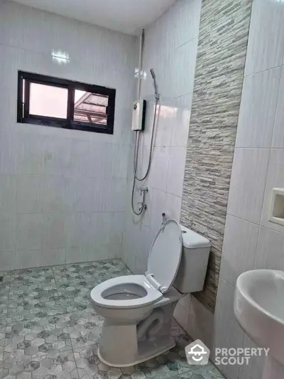 Modern bathroom with tiled walls and floor, featuring a toilet and shower area.