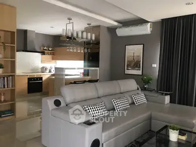 Modern living room with open kitchen, stylish decor, and comfortable seating in a contemporary apartment.