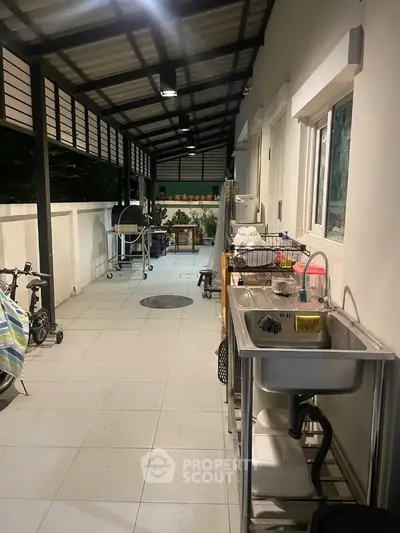 Spacious covered outdoor area with sink and barbecue setup, ideal for entertaining.