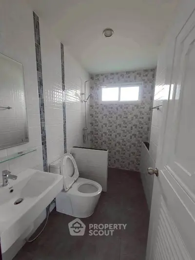 Modern bathroom with sleek fixtures and tiled walls, featuring a shower and toilet.