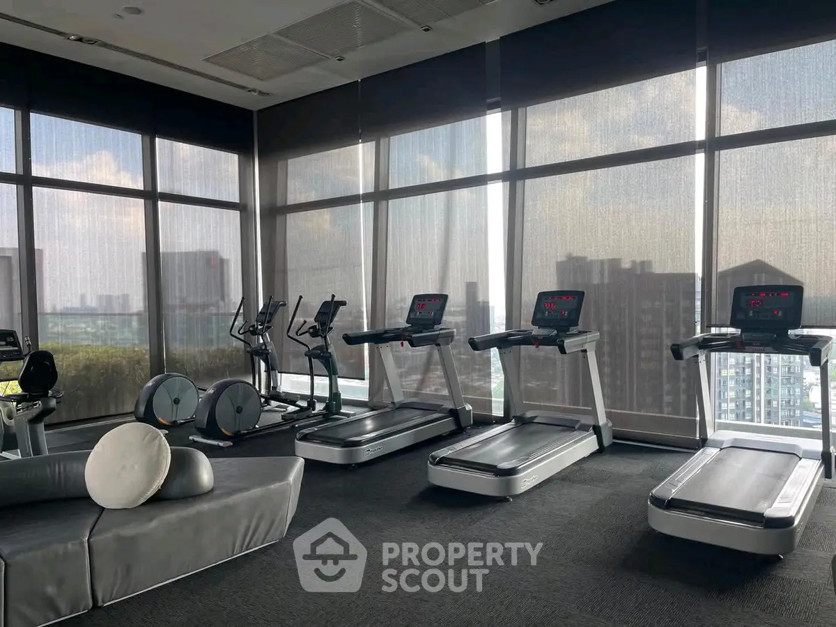 Modern gym with treadmills and city view in luxury apartment building