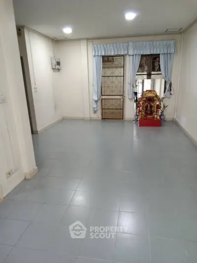 Spacious empty room with tiled floor and large window, perfect for customization.