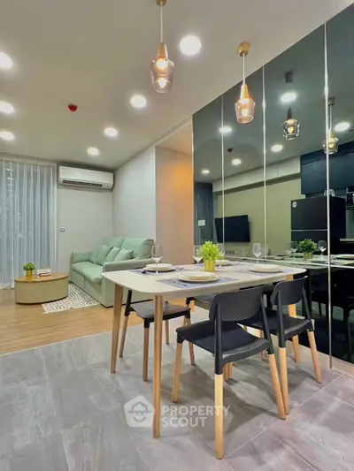 Modern dining area with stylish lighting and mirrored wall in open-plan living space.