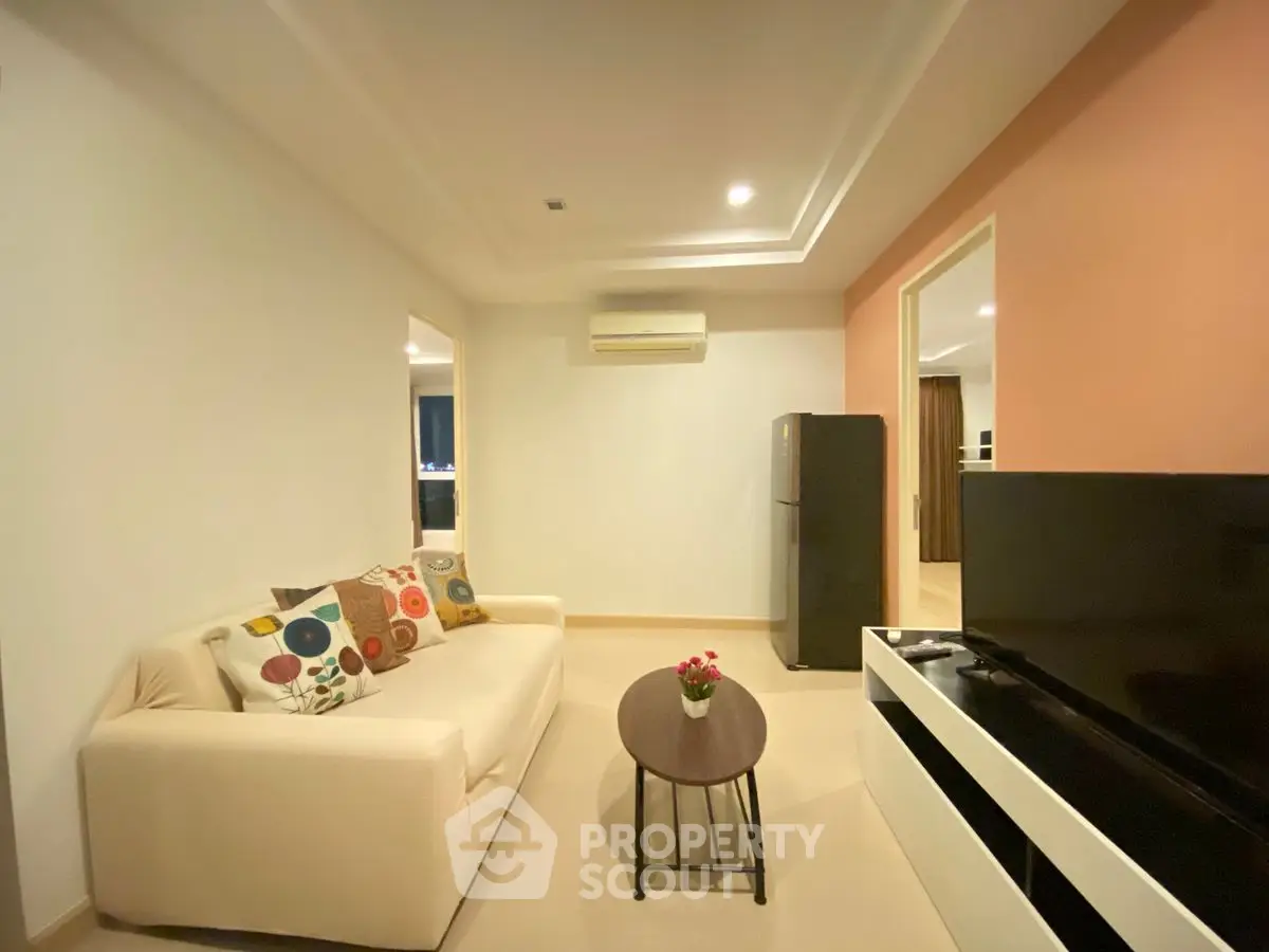 Cozy living room with modern decor and neutral tones, featuring a comfortable sofa and sleek TV setup.