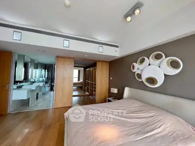 Spacious bedroom with modern decor and ensuite bathroom in luxury apartment.