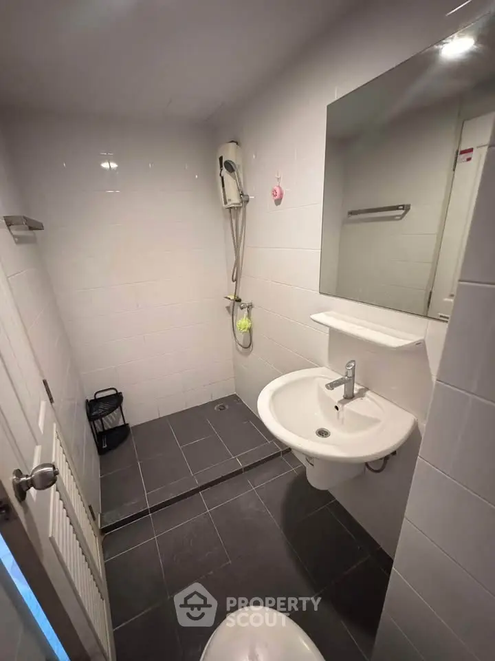 Modern bathroom with sleek fixtures and minimalist design, featuring a shower and stylish sink.