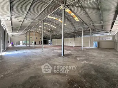 Spacious industrial warehouse with high ceilings and ample natural light, perfect for storage or manufacturing.