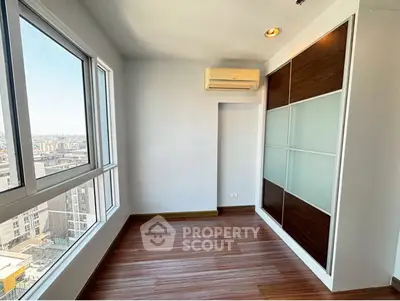 Bright room with large windows and built-in closet offering city views.