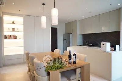 Modern kitchen with sleek cabinets and dining area, featuring elegant lighting and stylish decor.