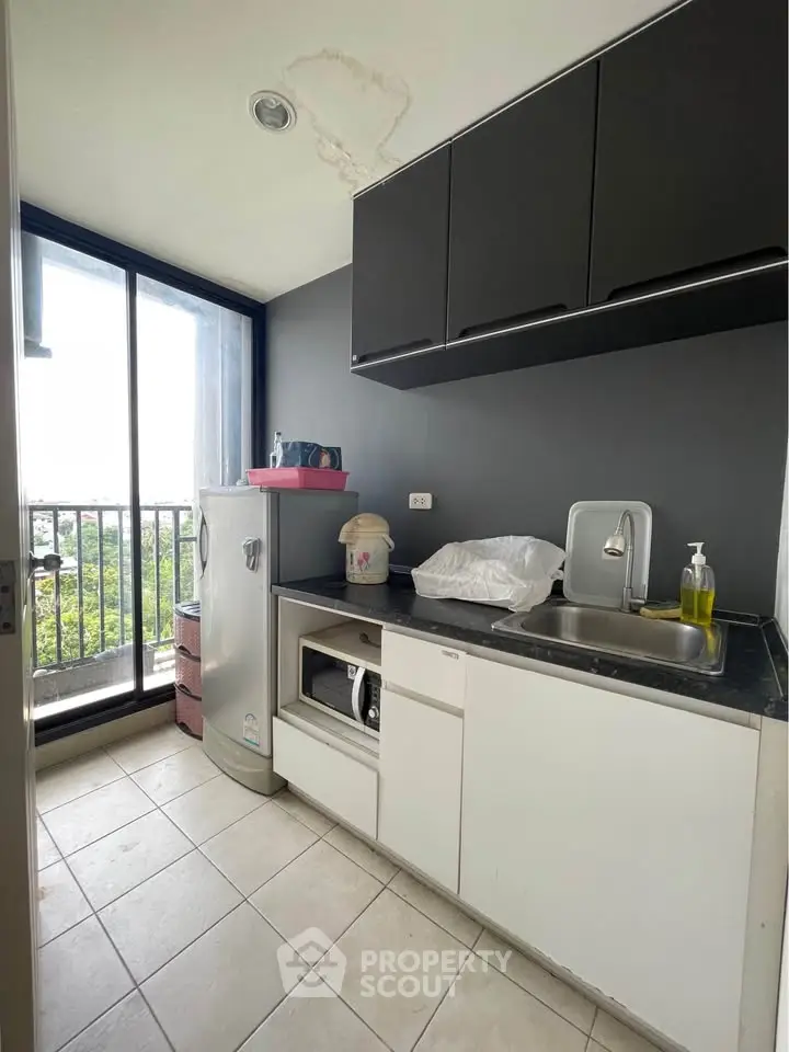 Modern compact kitchen with balcony view, featuring sleek cabinetry and essential appliances.