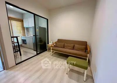Cozy living room with modern kitchen view, featuring a comfortable sofa and stylish decor.
