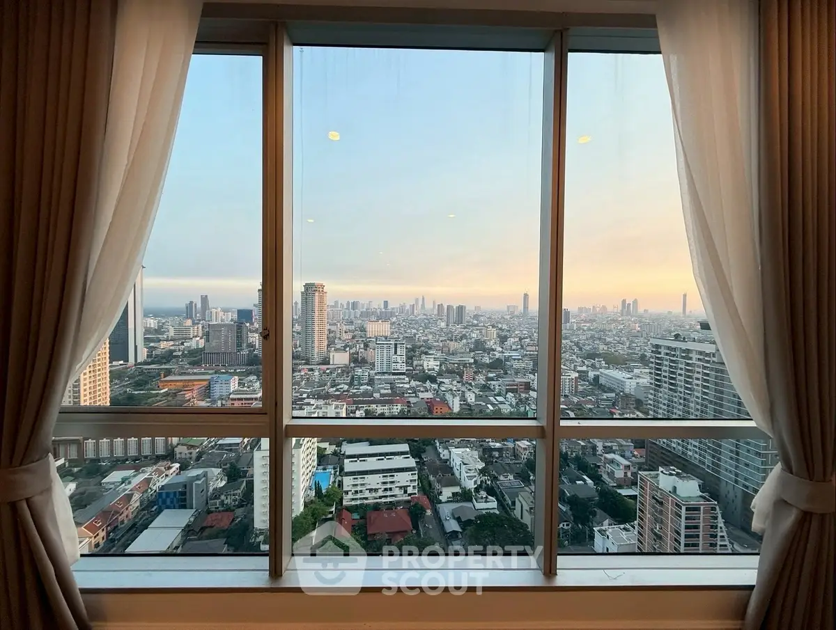Stunning cityscape view from high-rise apartment window at sunset.