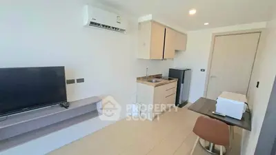 Modern compact living room with kitchenette, featuring sleek cabinetry and contemporary furnishings.