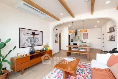 Charming living room with open kitchen, featuring wooden beams, stylish decor, and vibrant rug for a cozy ambiance.