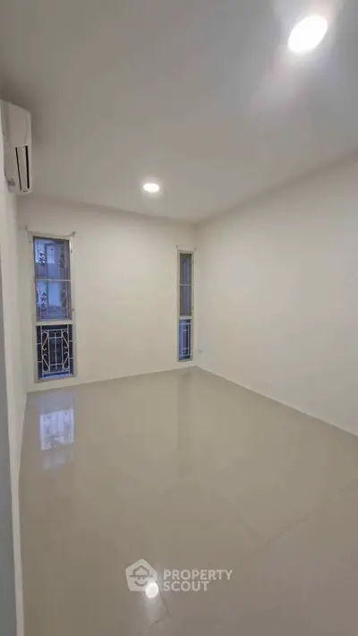 Spacious empty room with tiled flooring and large windows, perfect for customization.