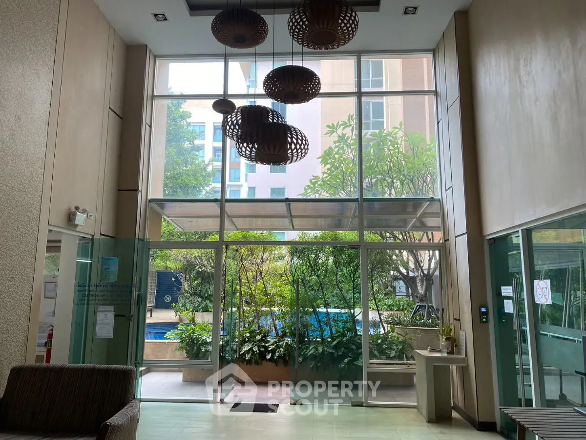 Spacious building entrance with modern lighting and lush greenery view.