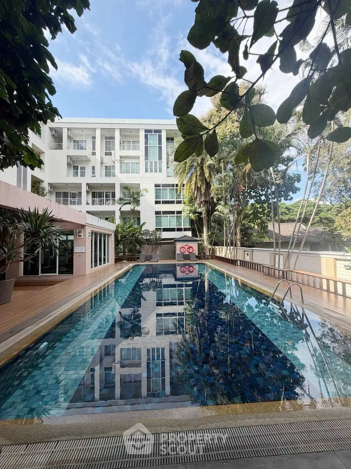 Luxurious apartment complex with a stunning outdoor pool and lush greenery, perfect for relaxation and leisure.