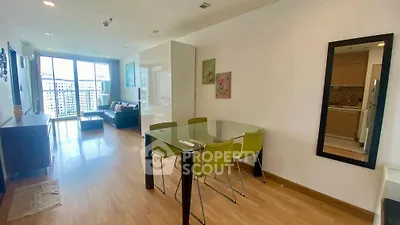 Spacious modern living room with glass dining table and large windows offering city views.
