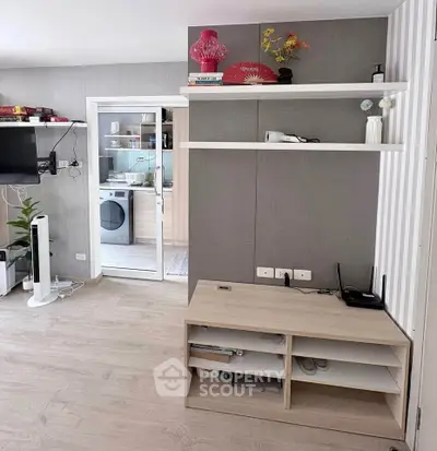 Modern living room with stylish shelving and view into a sleek kitchen with appliances.