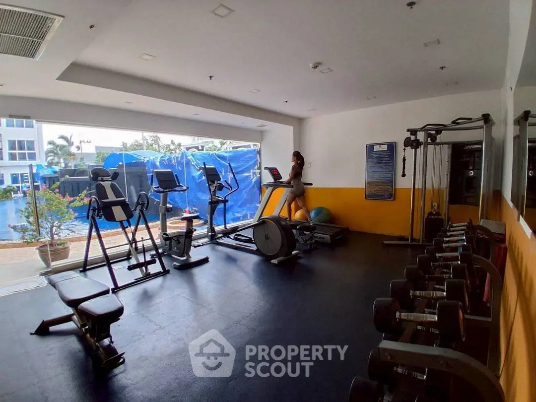 Spacious gym with modern equipment and outdoor view, perfect for fitness enthusiasts.