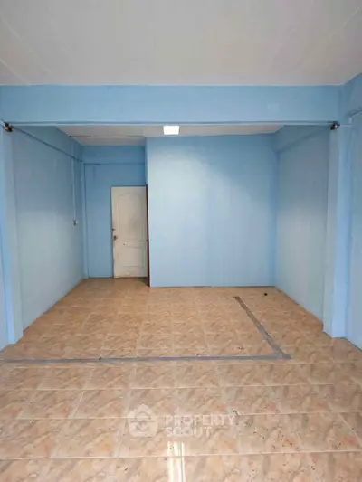 Spacious empty room with tiled floor and blue walls, ideal for customization.