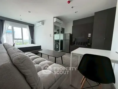 Modern studio apartment with open layout, featuring a cozy living area, bed, and compact kitchen with appliances.