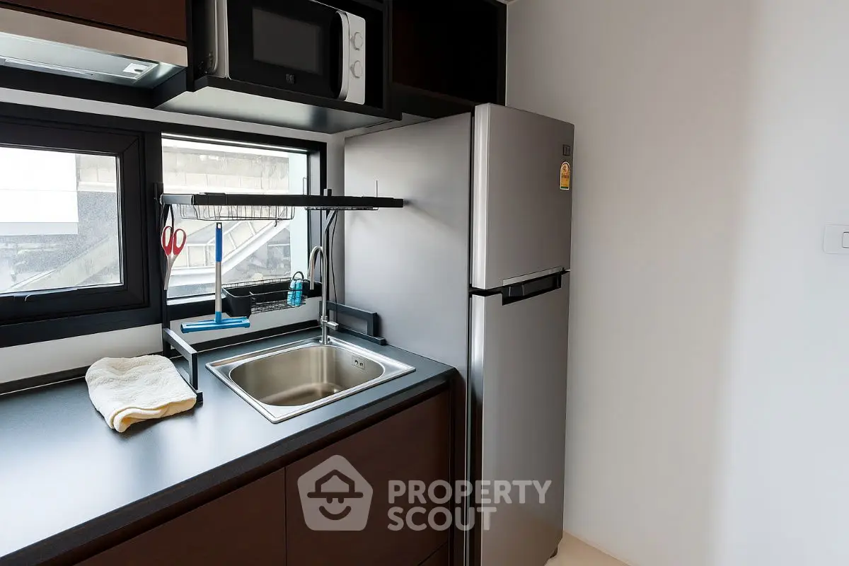 Modern kitchen with sleek design featuring stainless steel fridge and compact sink area.