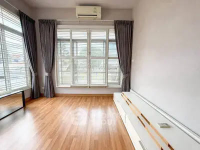 Spacious living room with large windows and wooden flooring, perfect for natural light lovers.